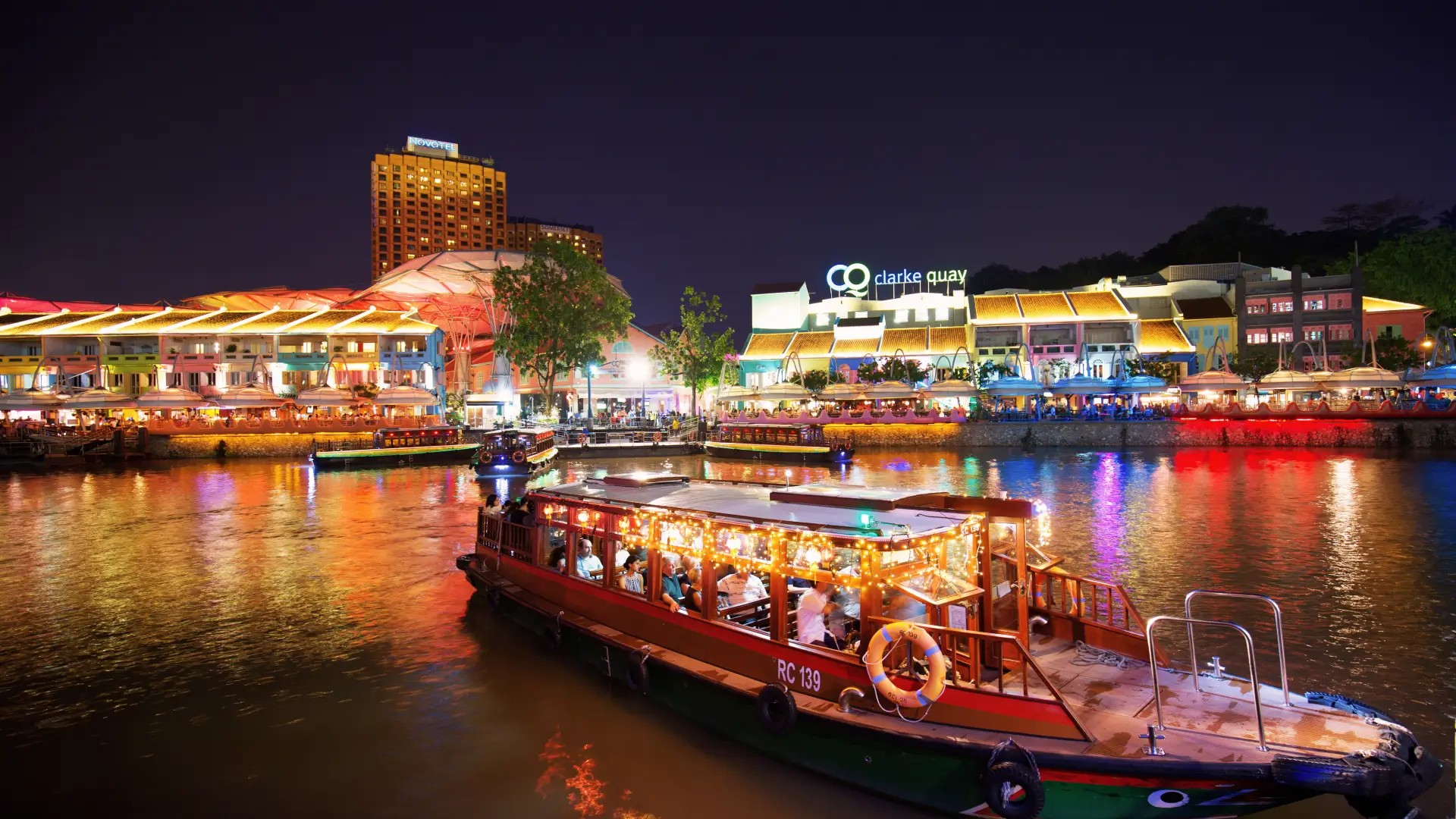 Singapore River cruise passing Clarke Quay under sparkling night lights.