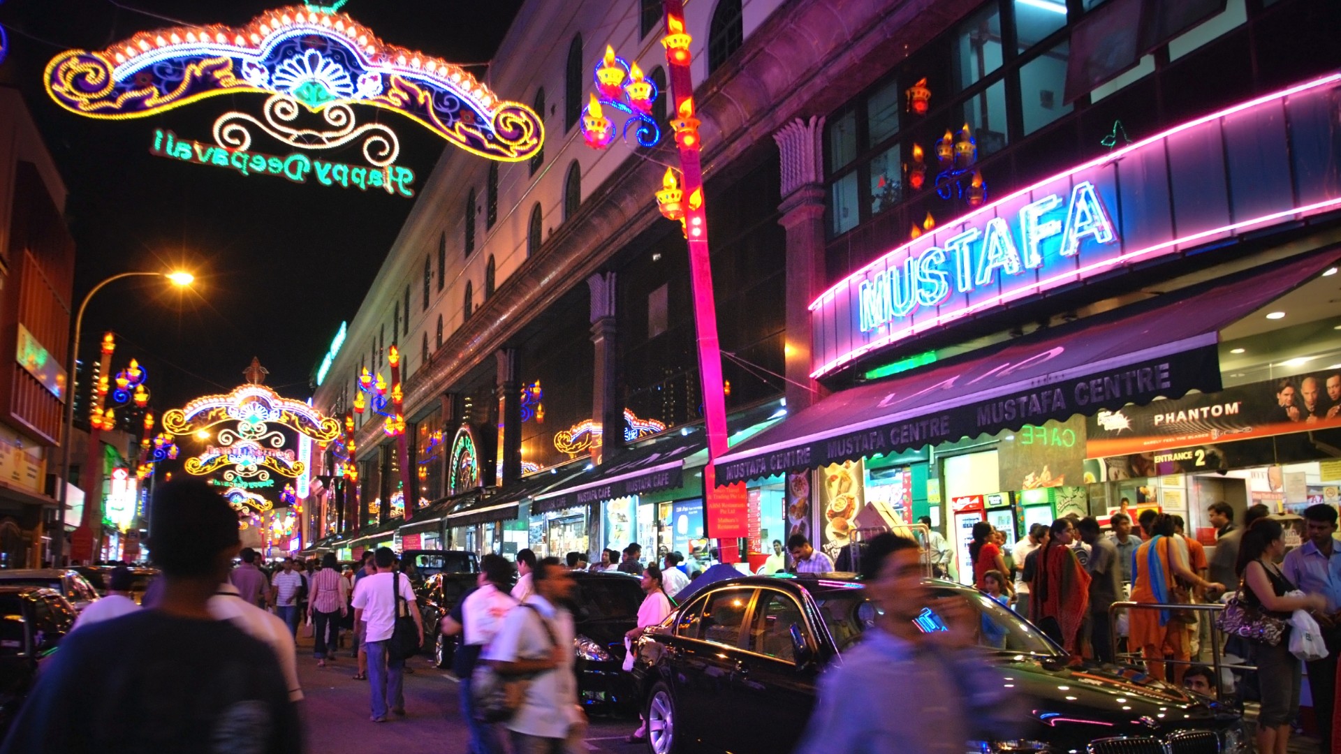Shoppers exploring Mustafa Centre and neon-lit streets of Little India, Singapore.