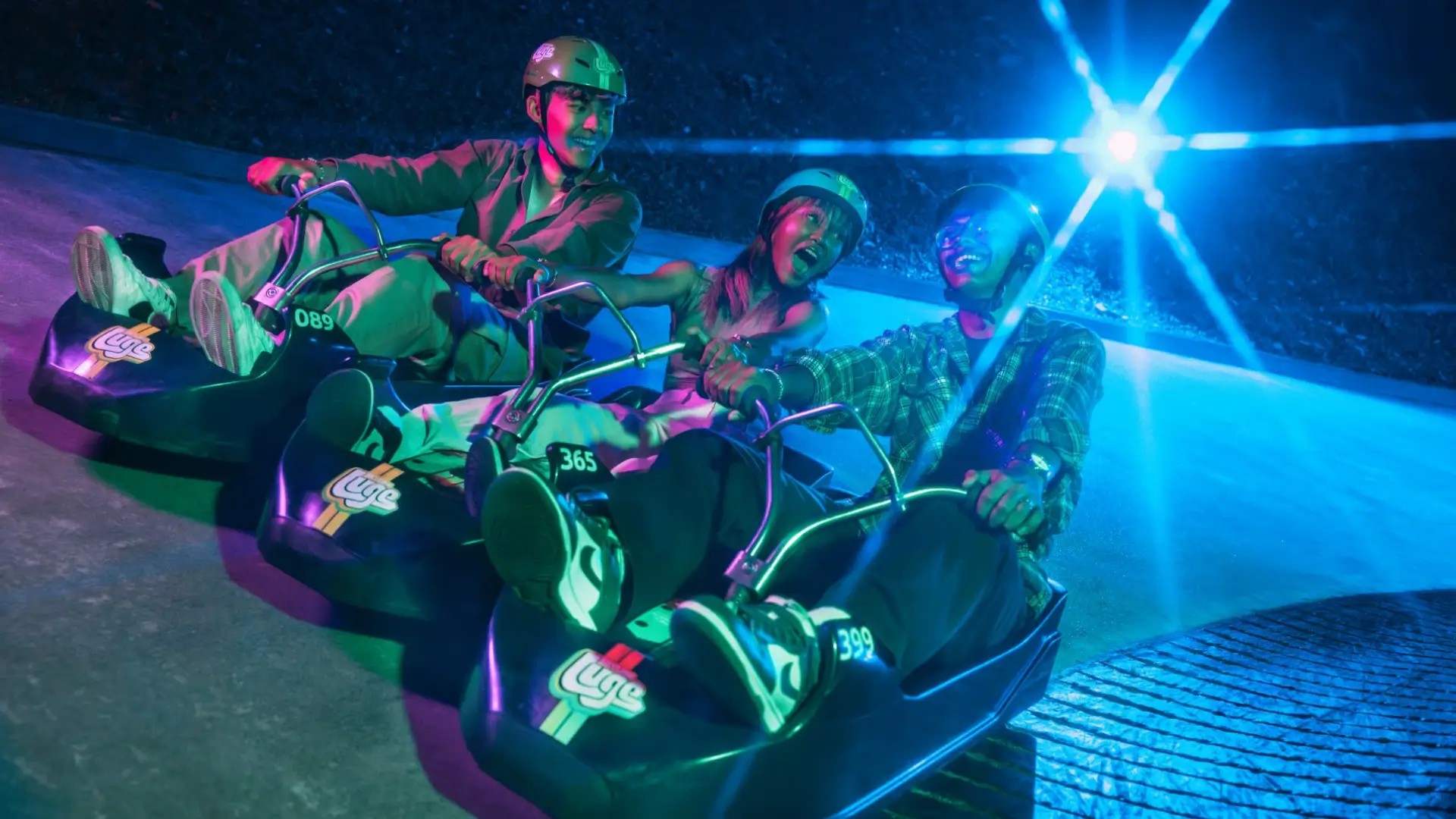 Group of friends enjoying a fun night ride on the Skyline Luge in Sentosa.