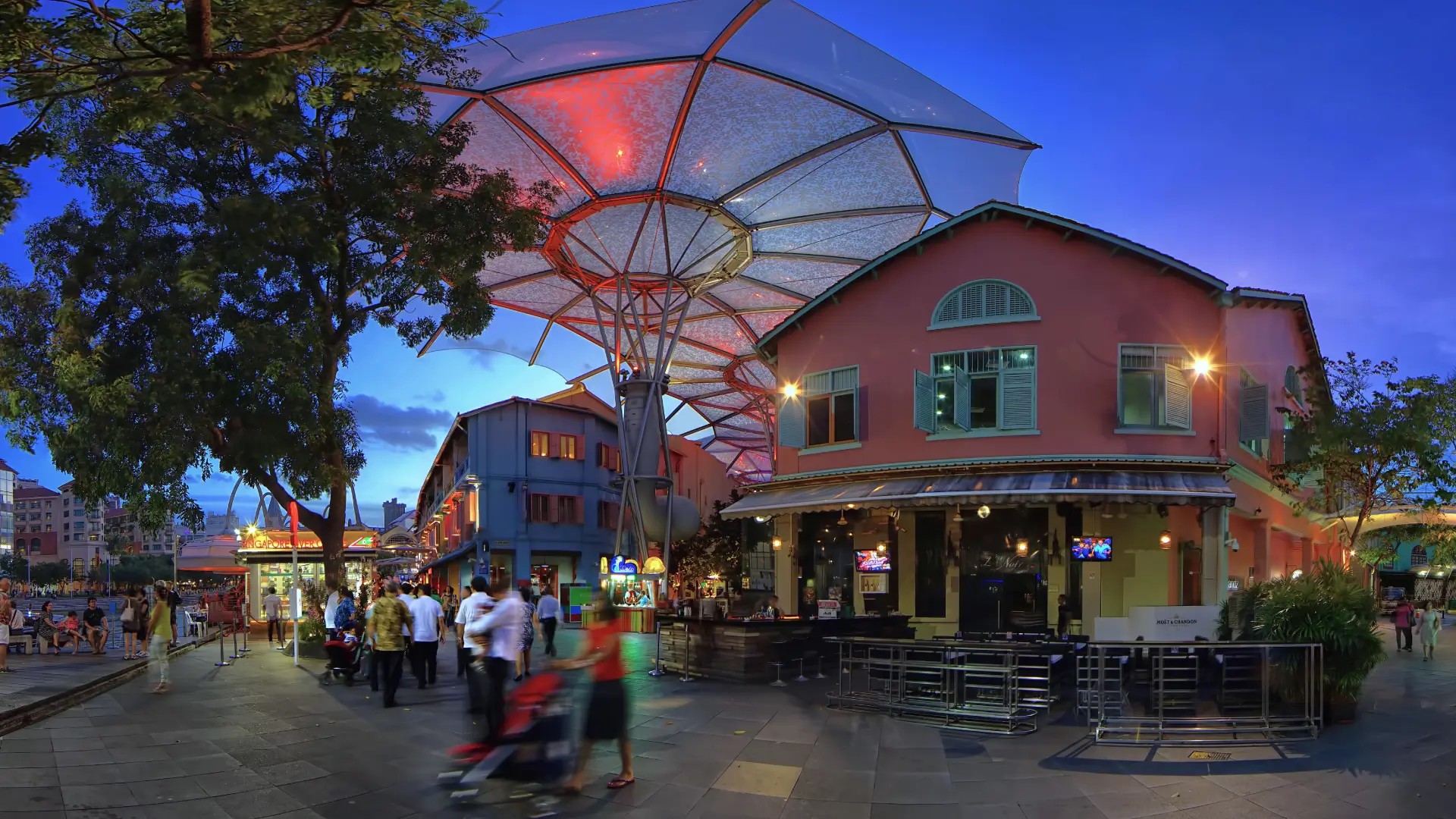 Evening scene at Clarke Quay with colourful riverside shophouses and modern canopy lights in Singapore.