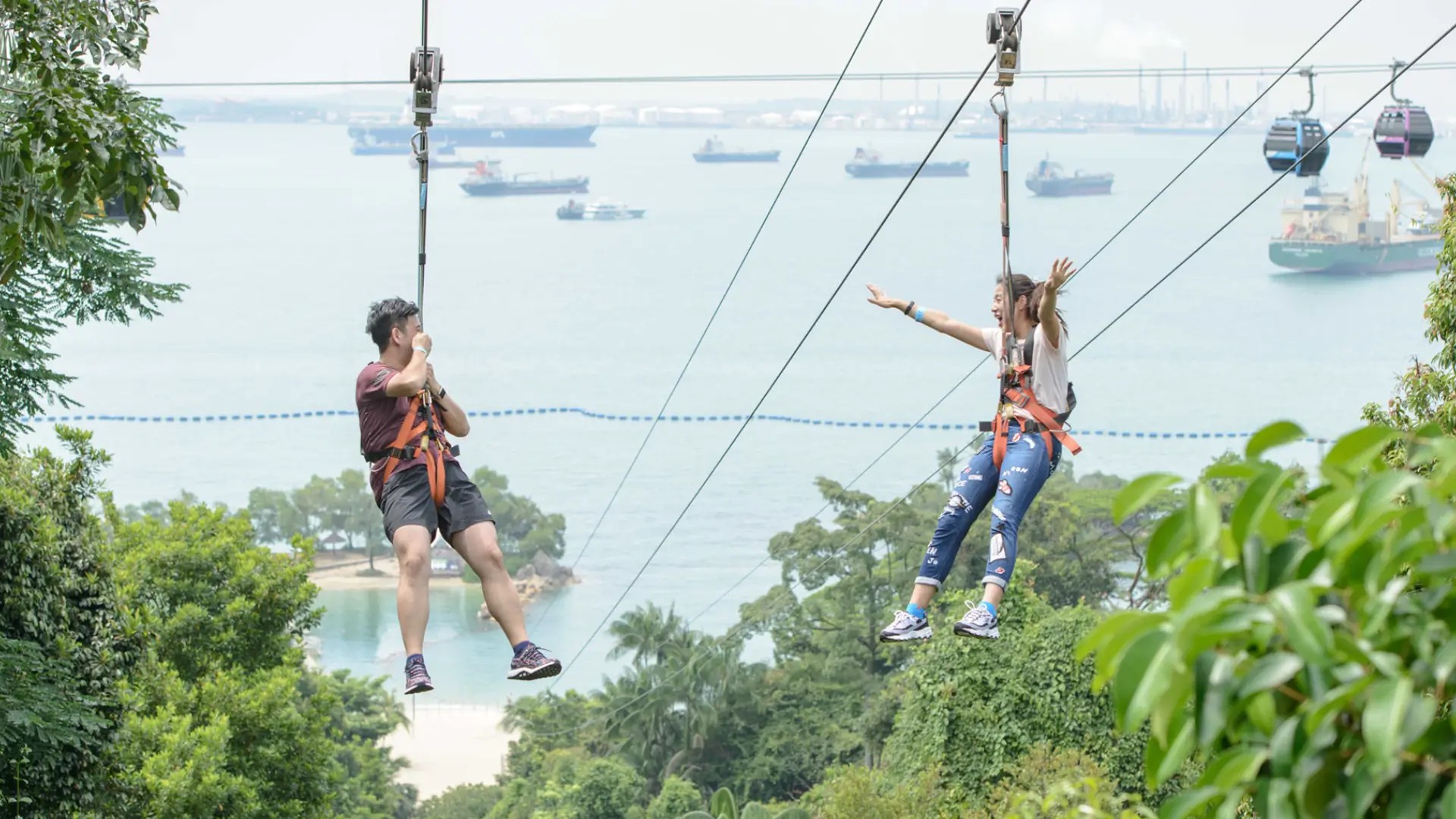 Friends ziplining over Sentosa’s beaches at Mega Adventure Park in Singapore.