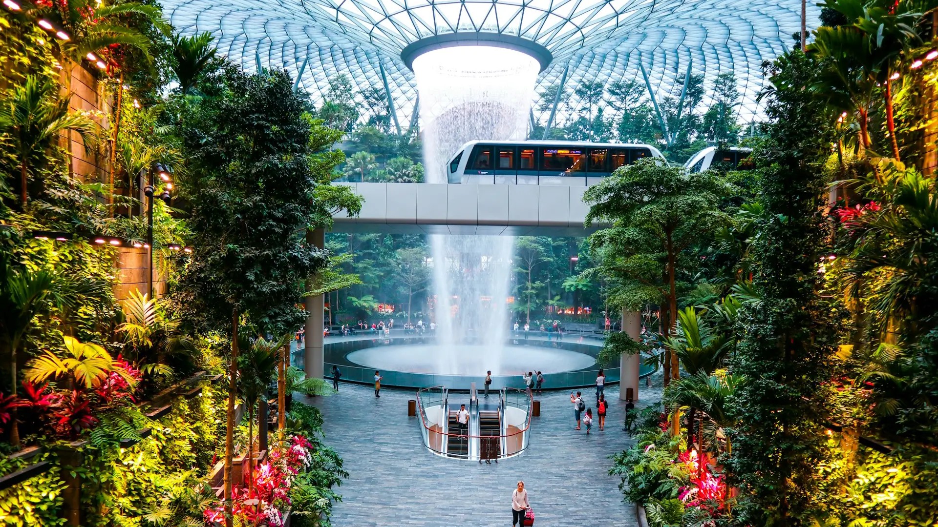 The Rain Vortex waterfall and indoor forest with Skytrain passing through Jewel Changi Airport Singapore.