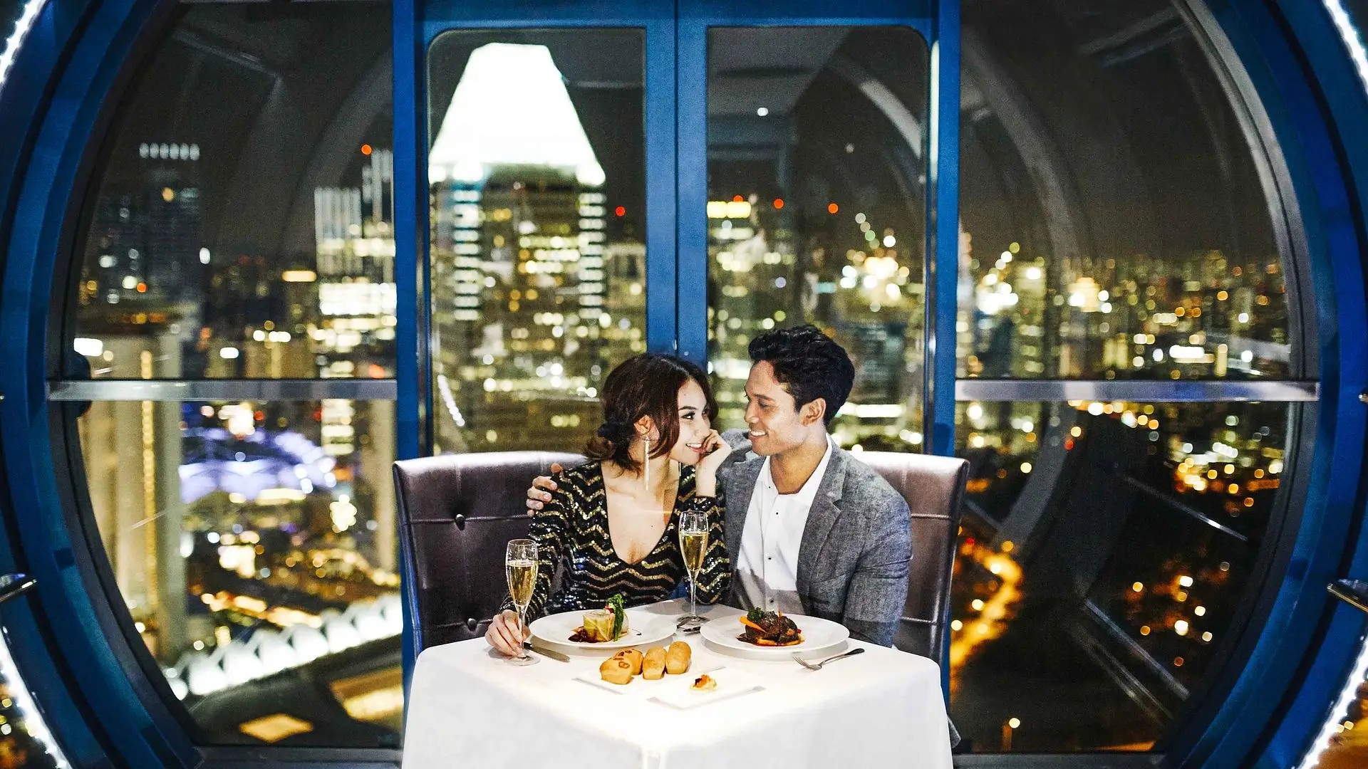 Couple enjoying a private dinner inside a Singapore Flyer capsule with panoramic night views of the city skyline.