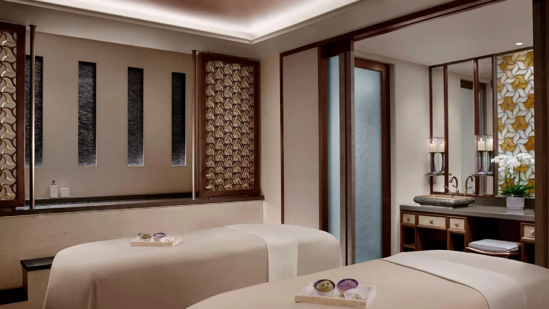 Elegant couples’ treatment suite at The Ritz-Carlton Spa in Singapore, featuring warm lighting and tranquil decor.