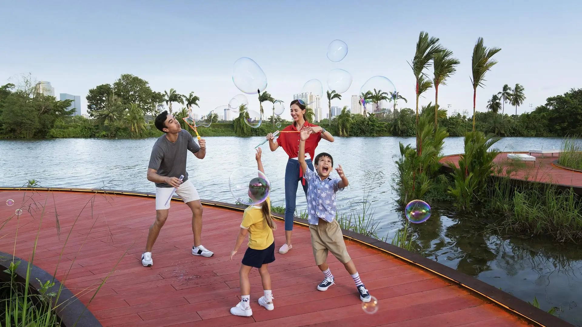 Family enjoying outdoor play at Jurong Lake Gardens, with kids blowing bubbles beside the lake in Singapore.