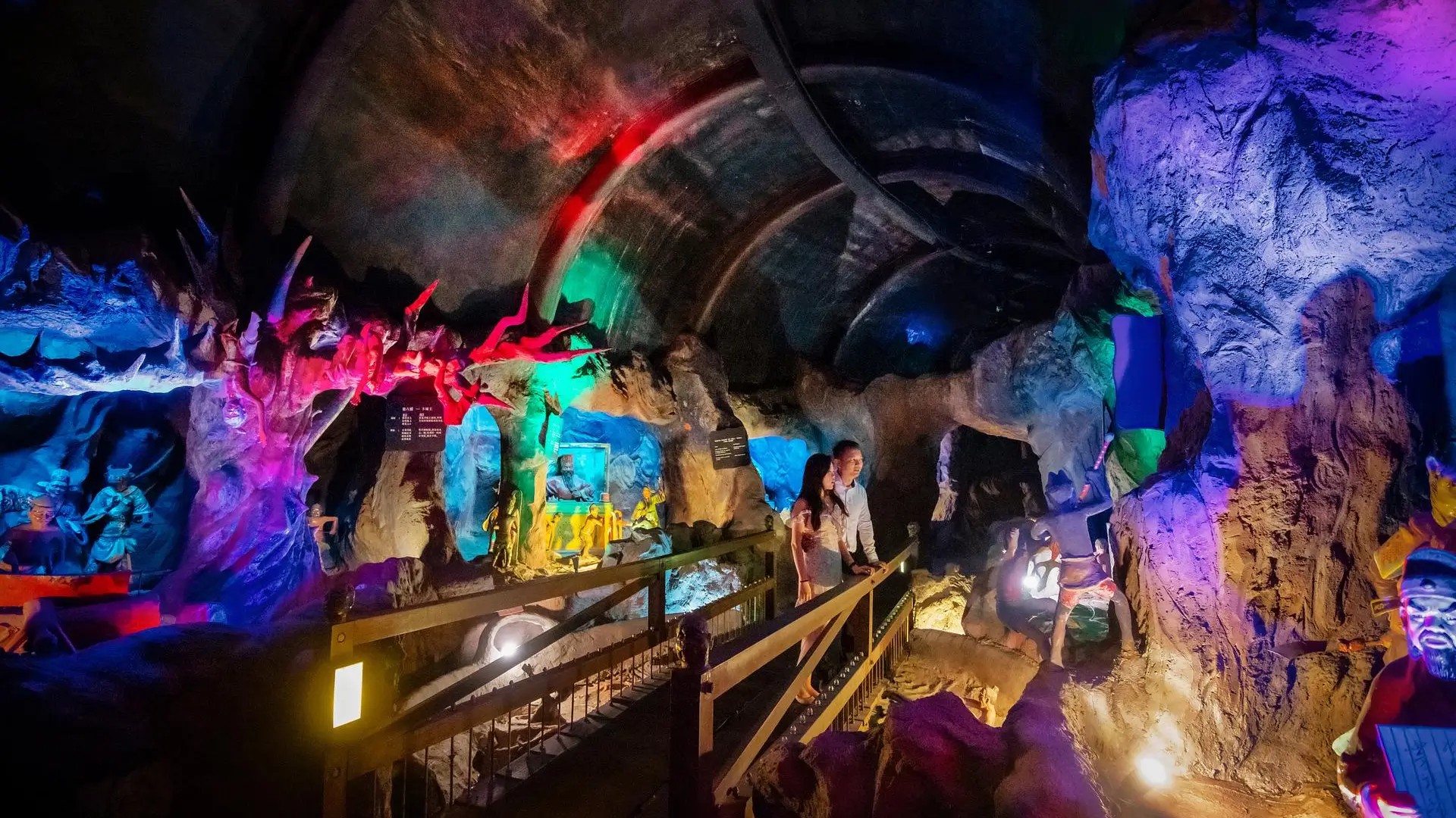 Visitors walking through a colourful cave diorama at Haw Par Villa, showcasing vivid scenes from Chinese mythology.
