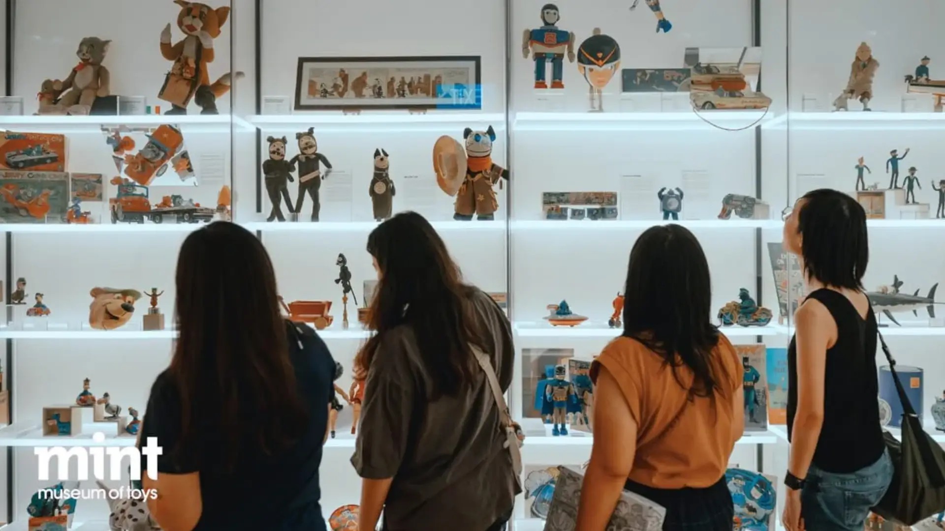 Visitors exploring toy displays at the MINT Museum of Toys in Singapore, featuring vintage figurines and collectibles.