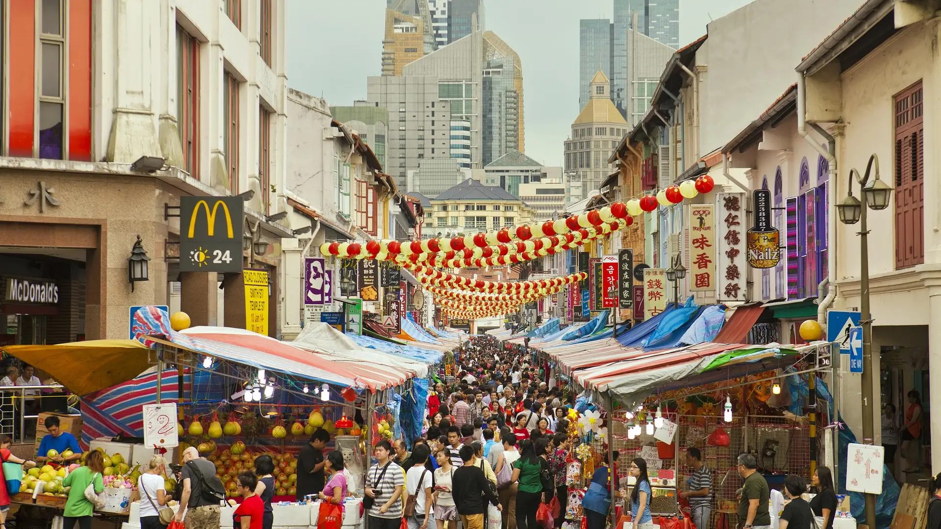 Crowded Chinatown street market in Singapore with red lanterns and food stalls