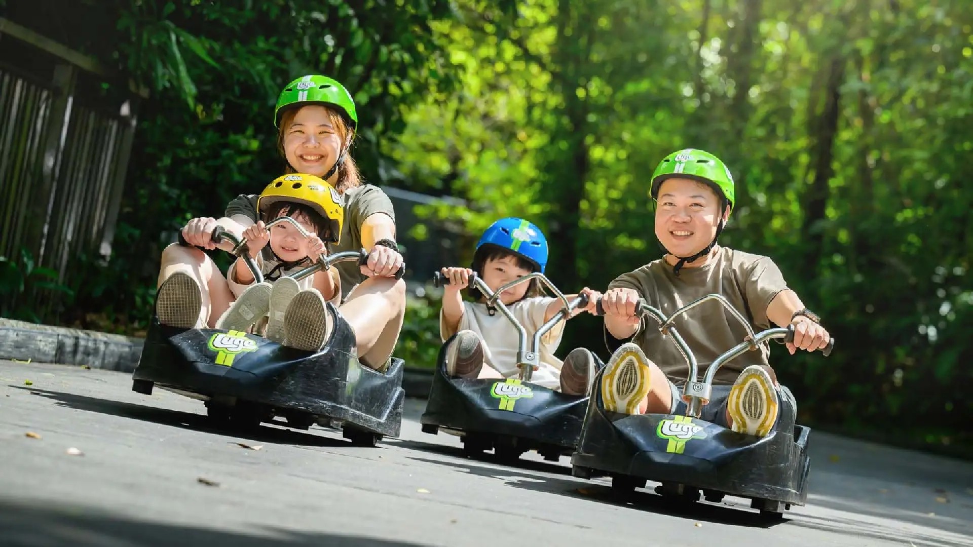 Skyline Luge Singapore - a family of four on Luge carts with one child riding tandem