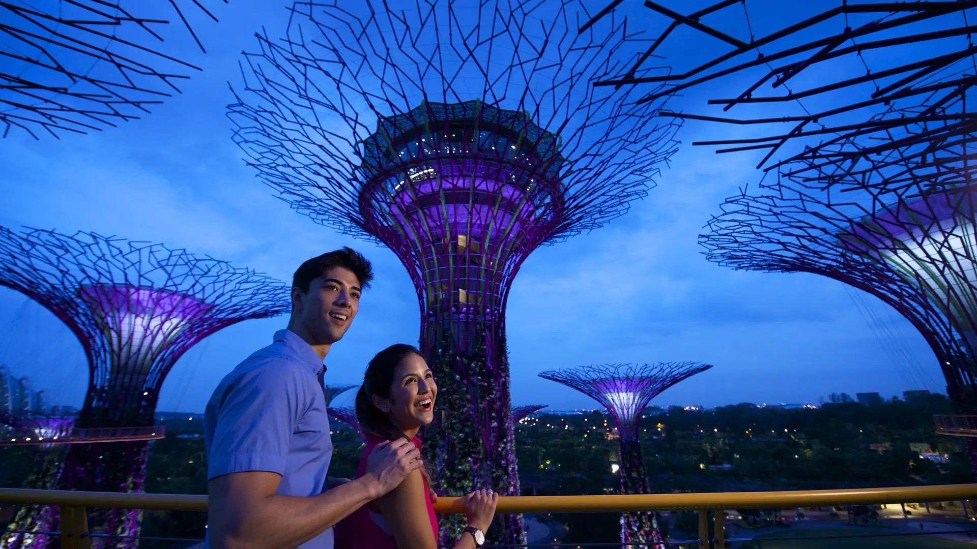 Couple watching the Gardens by the Bay Supertree light show glowing at night in Singapore.