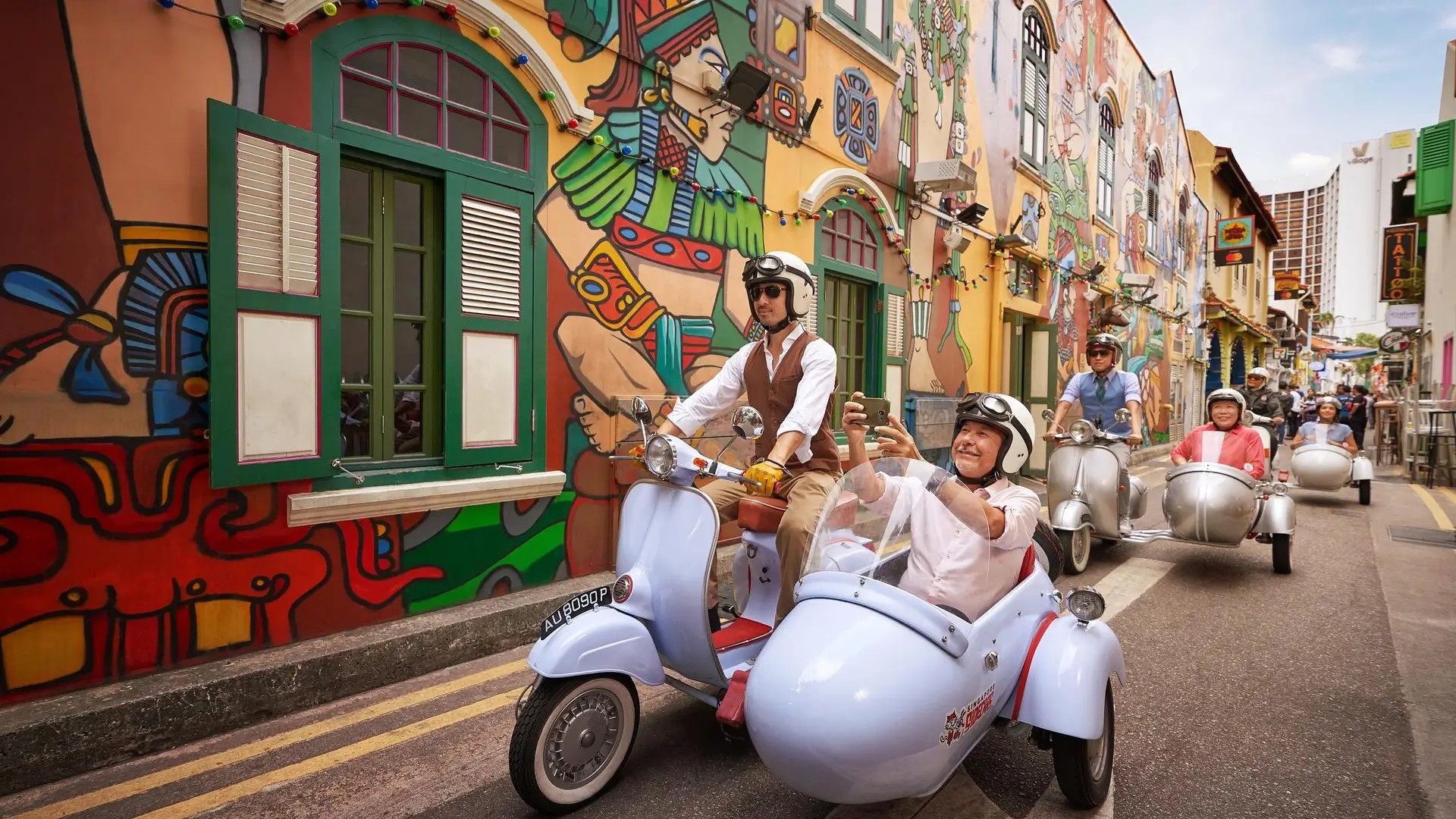 Visitors enjoying a vintage scooter tour through the colourful streets of Haji Lane in Singapore.