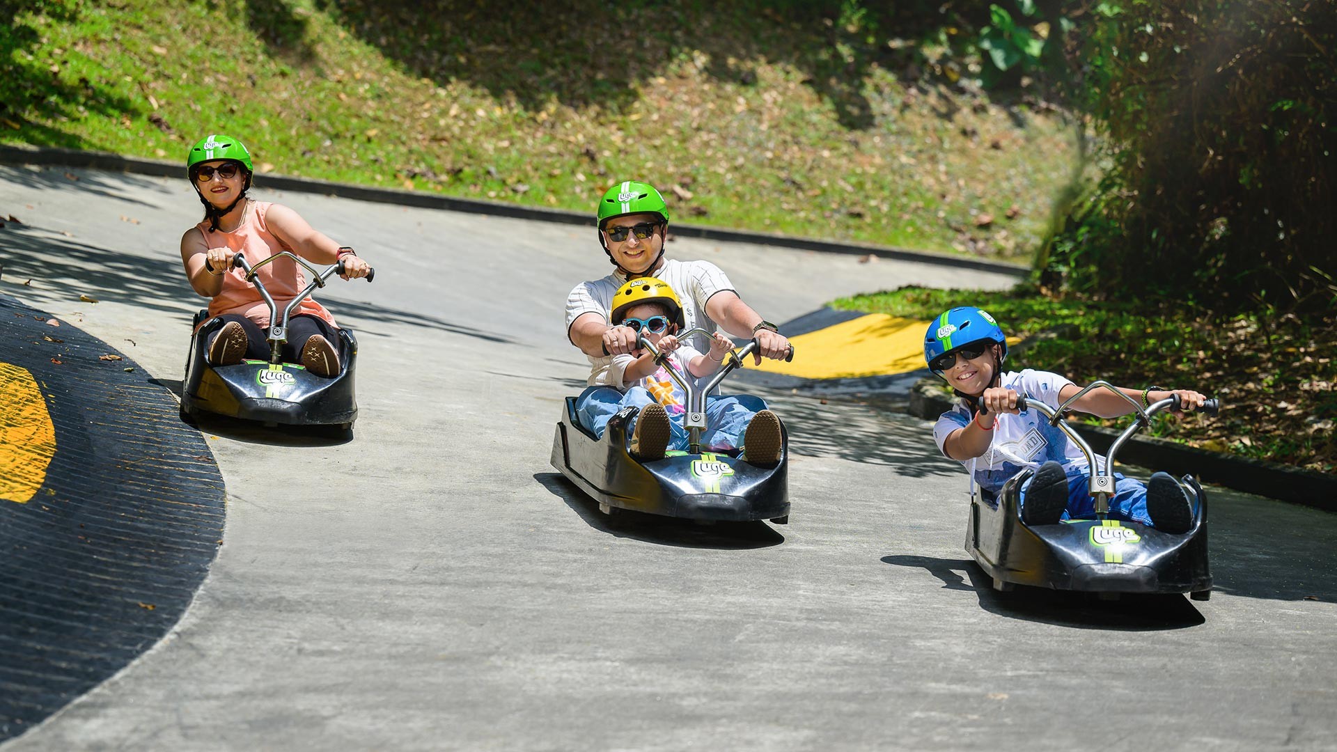 Family enjoying a luge ride together at Skyline Luge Tongyeong, riding downhill tracks in a safe outdoor setting