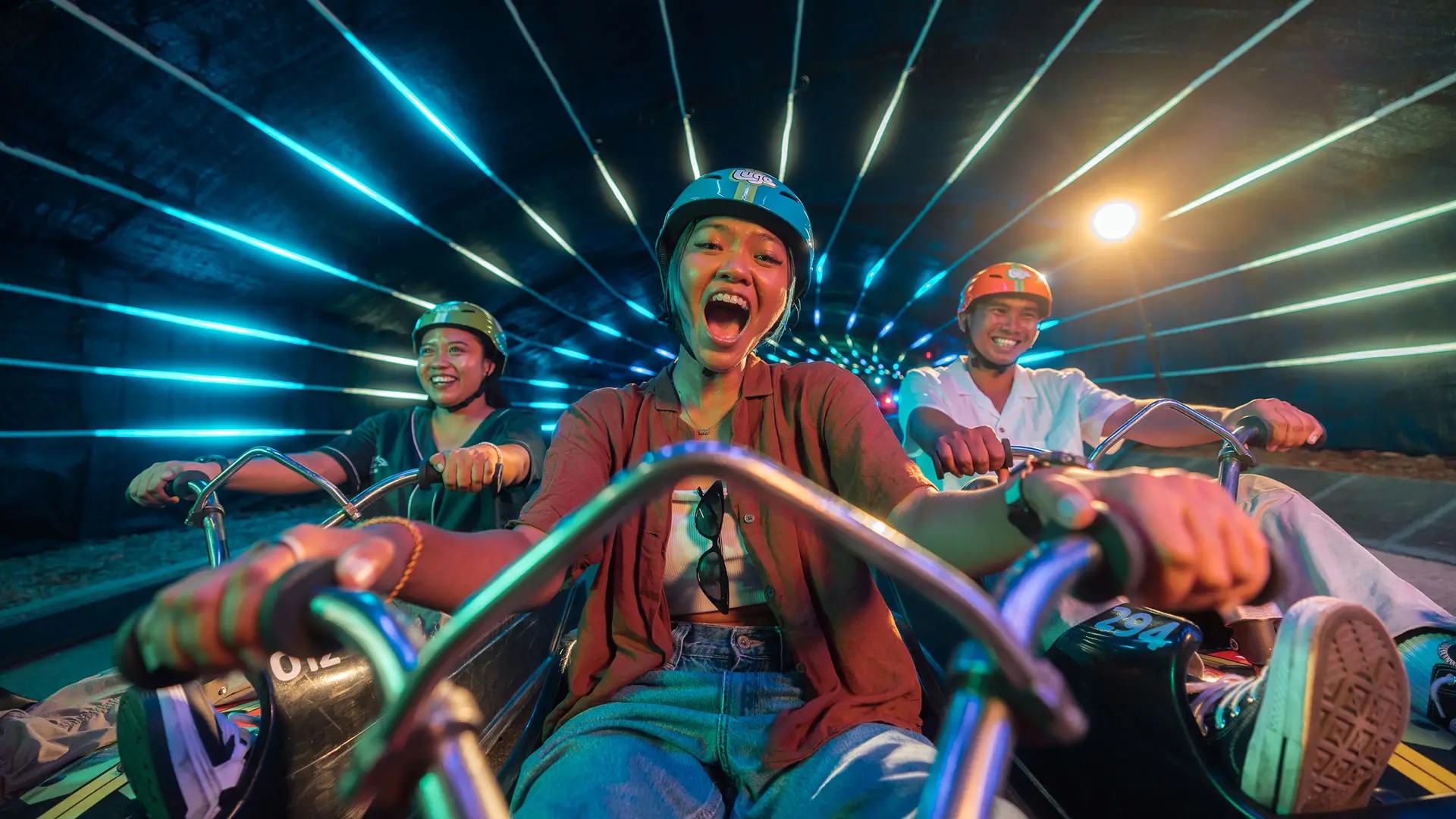 Riders enjoying Skyline Luge Singapore Night Luge through a neon-lit tunnel on Sentosa Island