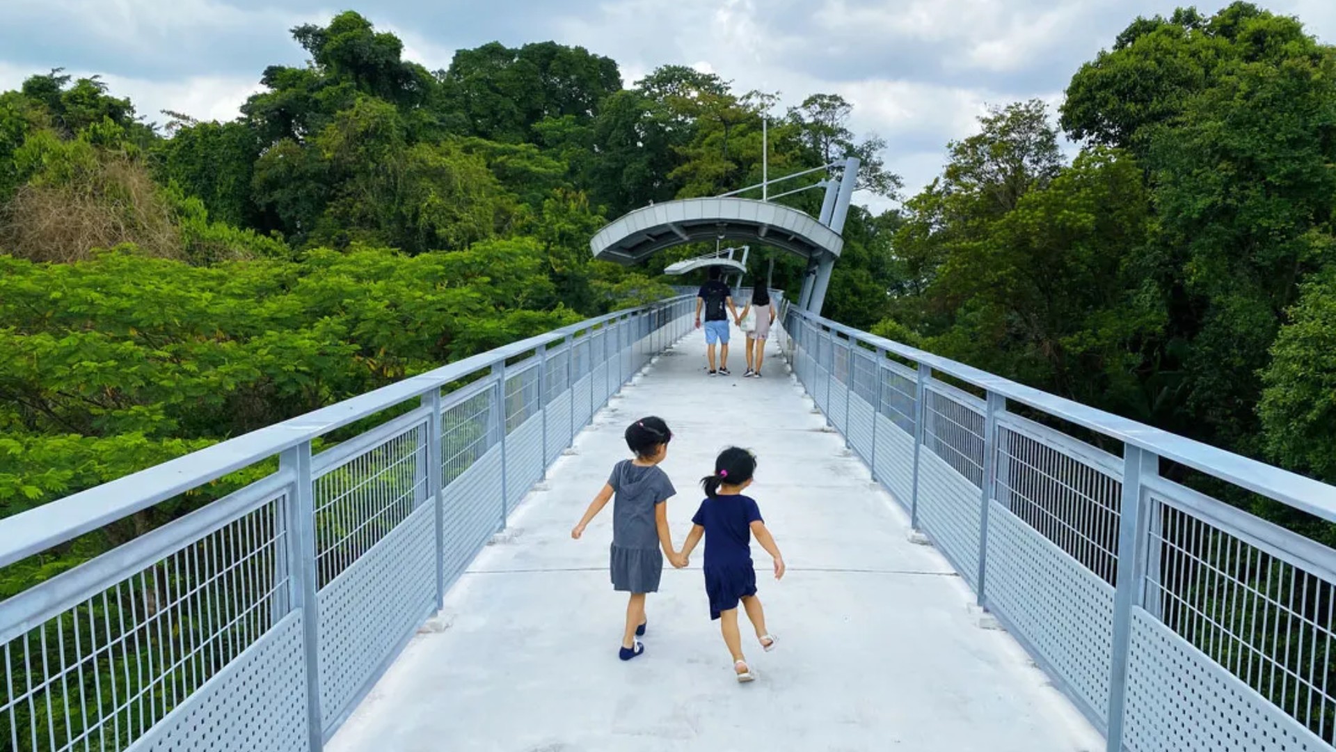 Visitors strolling along Fort Siloso Skywalk in Sentosa, a free elevated walkway offering rainforest canopy and coastal views.
