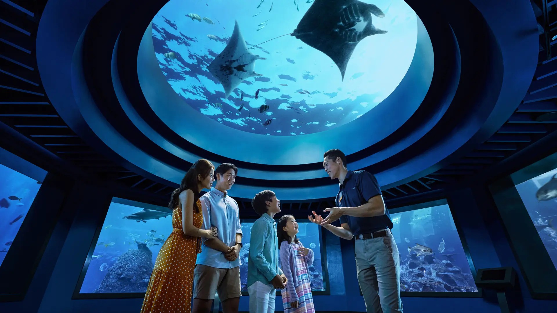 Family exploring the Singapore Oceanarium at Resorts World Sentosa with manta rays swimming overhead