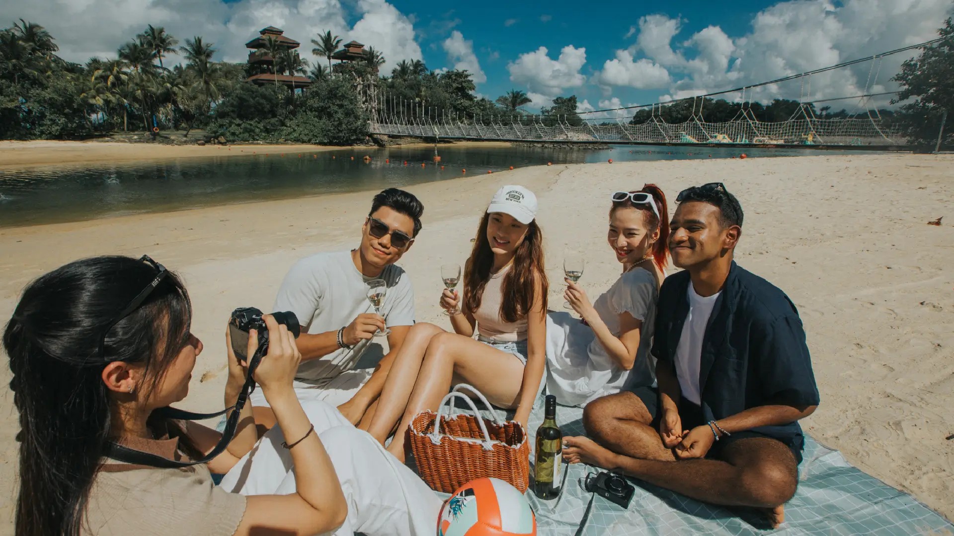 Friends enjoying a picnic on Palawan Beach, Sentosa Island, with lagoon waters and tropical surroundings