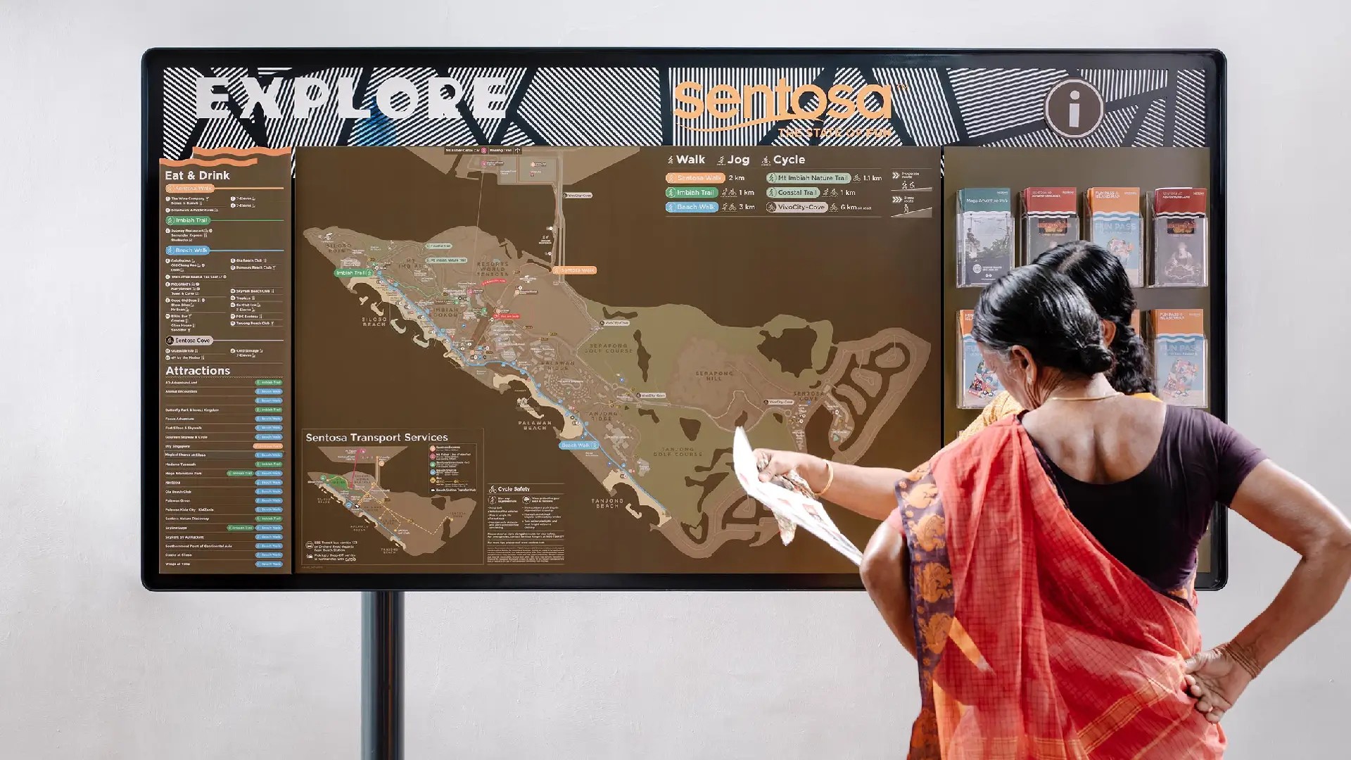 Visitor looking at a Sentosa attractions map showing transport routes, walking paths, and key areas around the island
