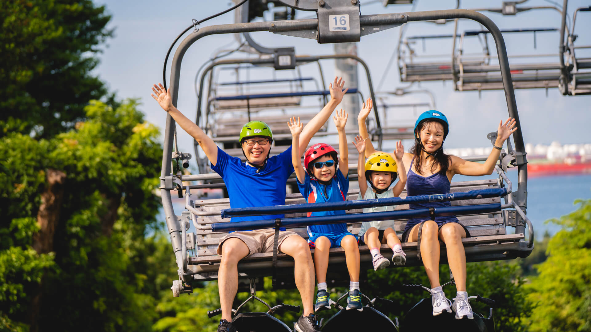 Family riding the Skyride at Sentosa with hands raised, enjoying an exciting adventure experience