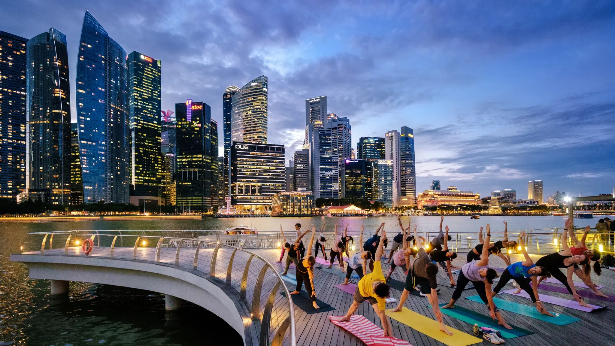 Outdoor yoga session at Marina Bay waterfront with Singapore skyline at dusk