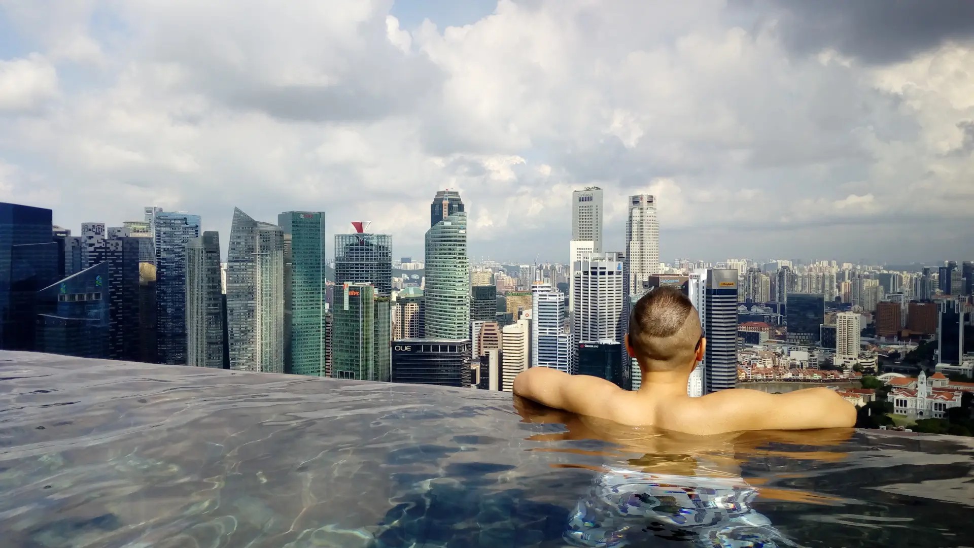 Person relaxing in an infinity pool overlooking the Singapore city skyline