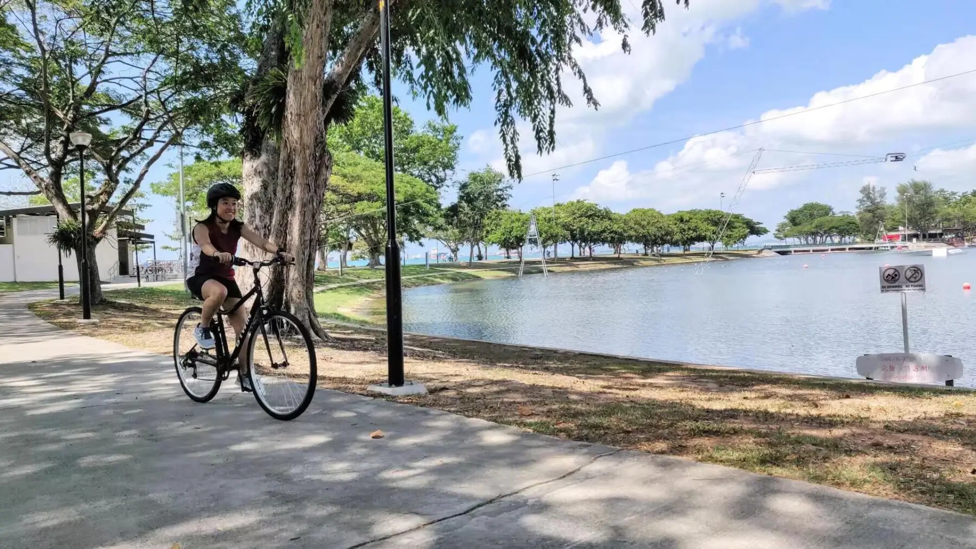 Cyclist riding along the waterfront path at East Coast Park in Singapore on a sunny day