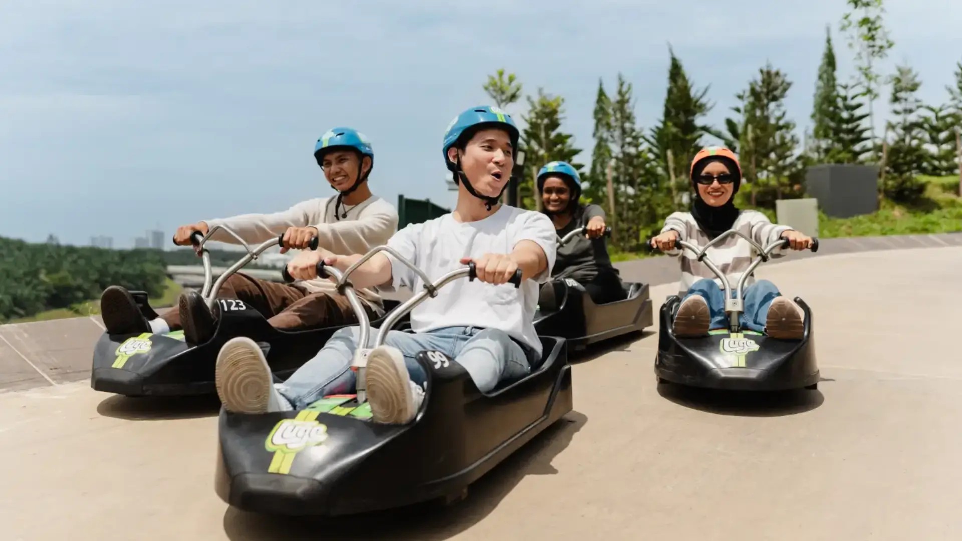 Visitors riding Skyline Luge carts along an outdoor track in Kuala Lumpur.