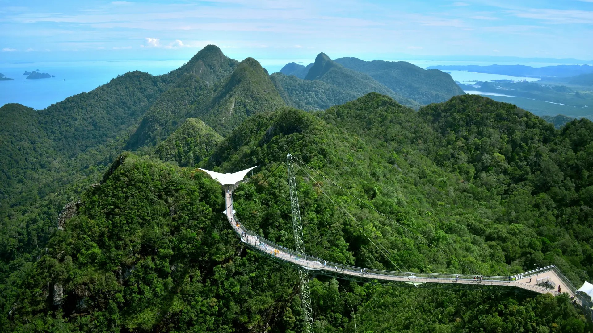 Aerial view of the Langkawi Sky Bridge spanning lush rainforest-covered mountains, with panoramic views of the Andaman Sea and surrounding islands in Malaysia.