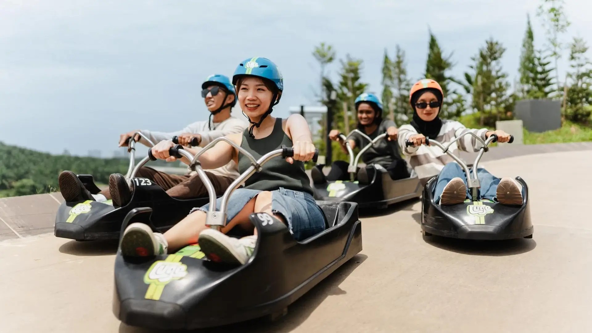 Visitors riding Skyline Luge carts on an outdoor track at Skyline Luge Kuala Lumpur