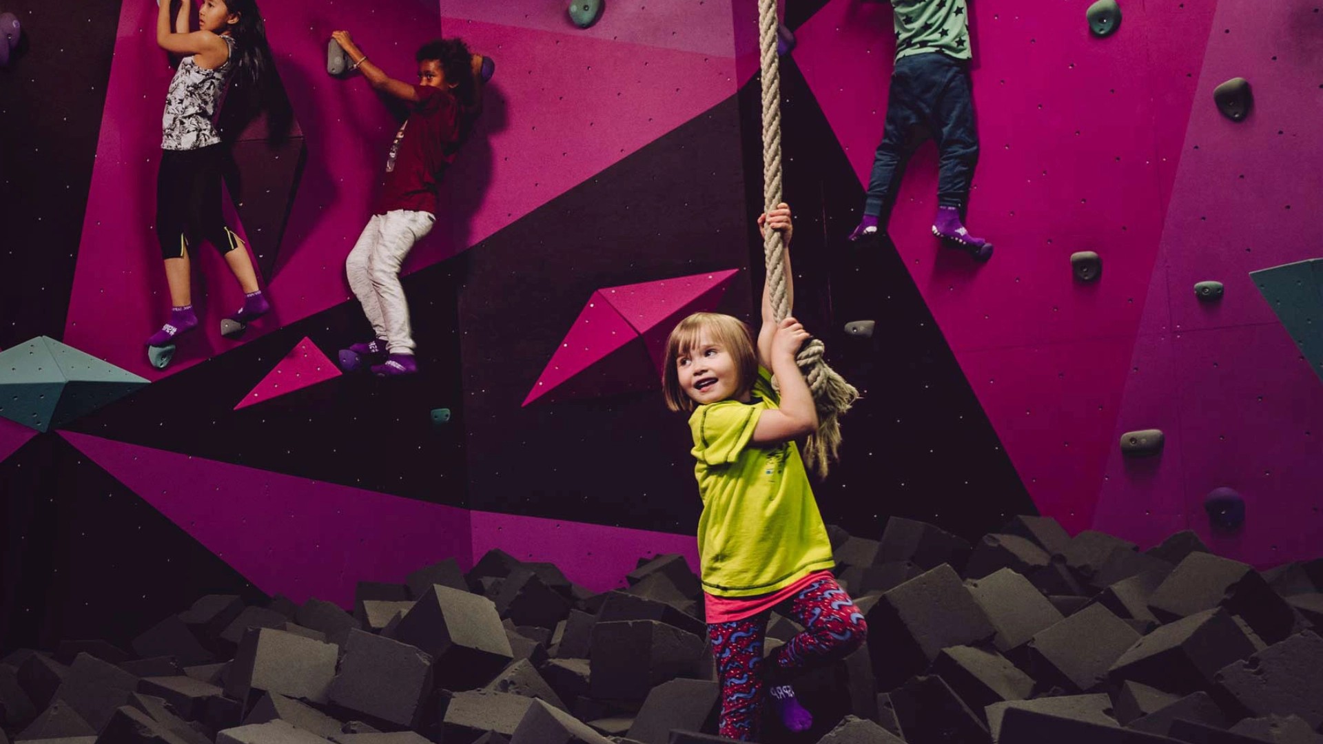 Children climbing an indoor climbing wall and rope over a foam pit at SuperPark Malaysia
