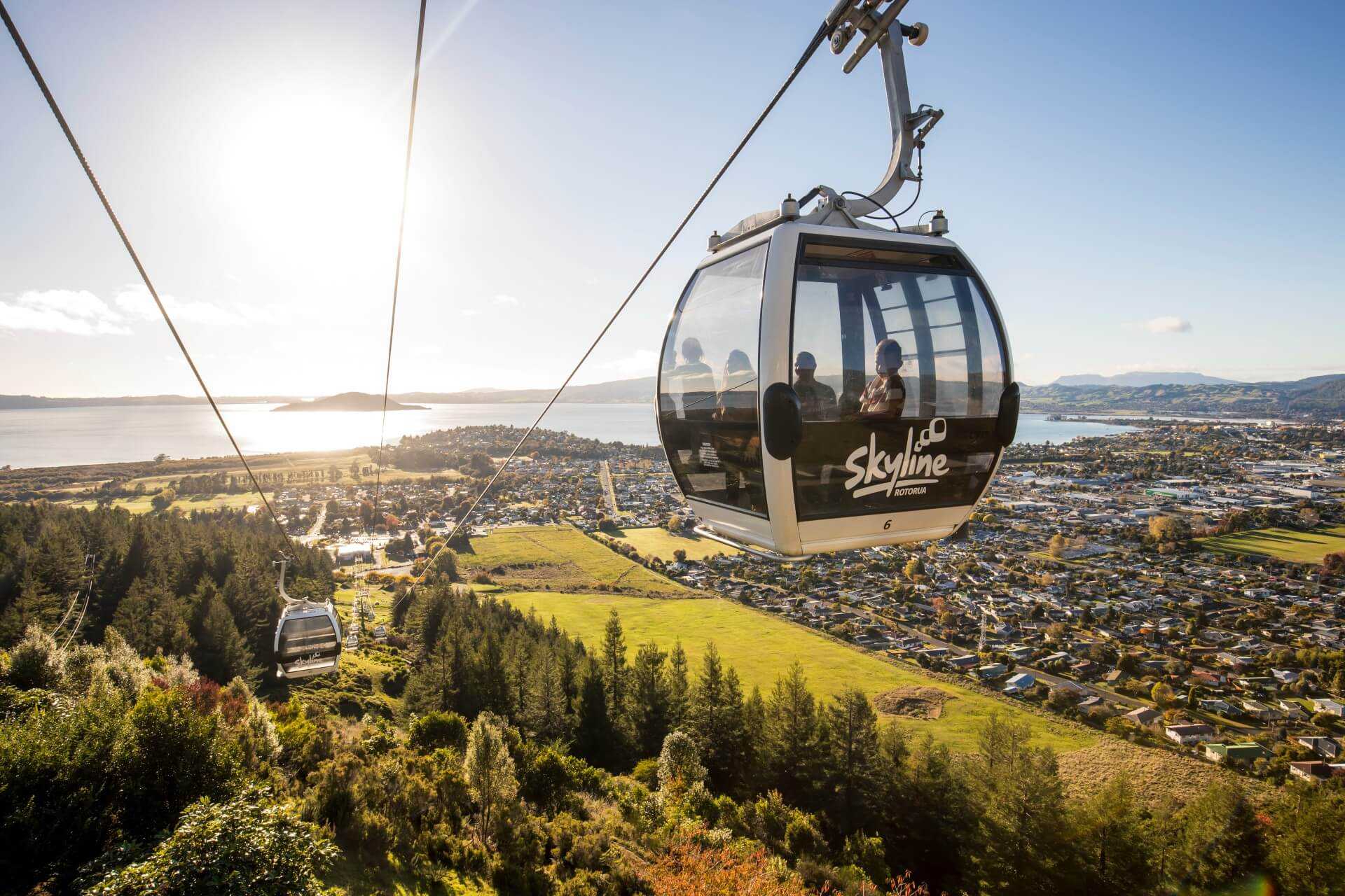 The Skyline Rotorua reaches the top terminal building with a family in a cabin.