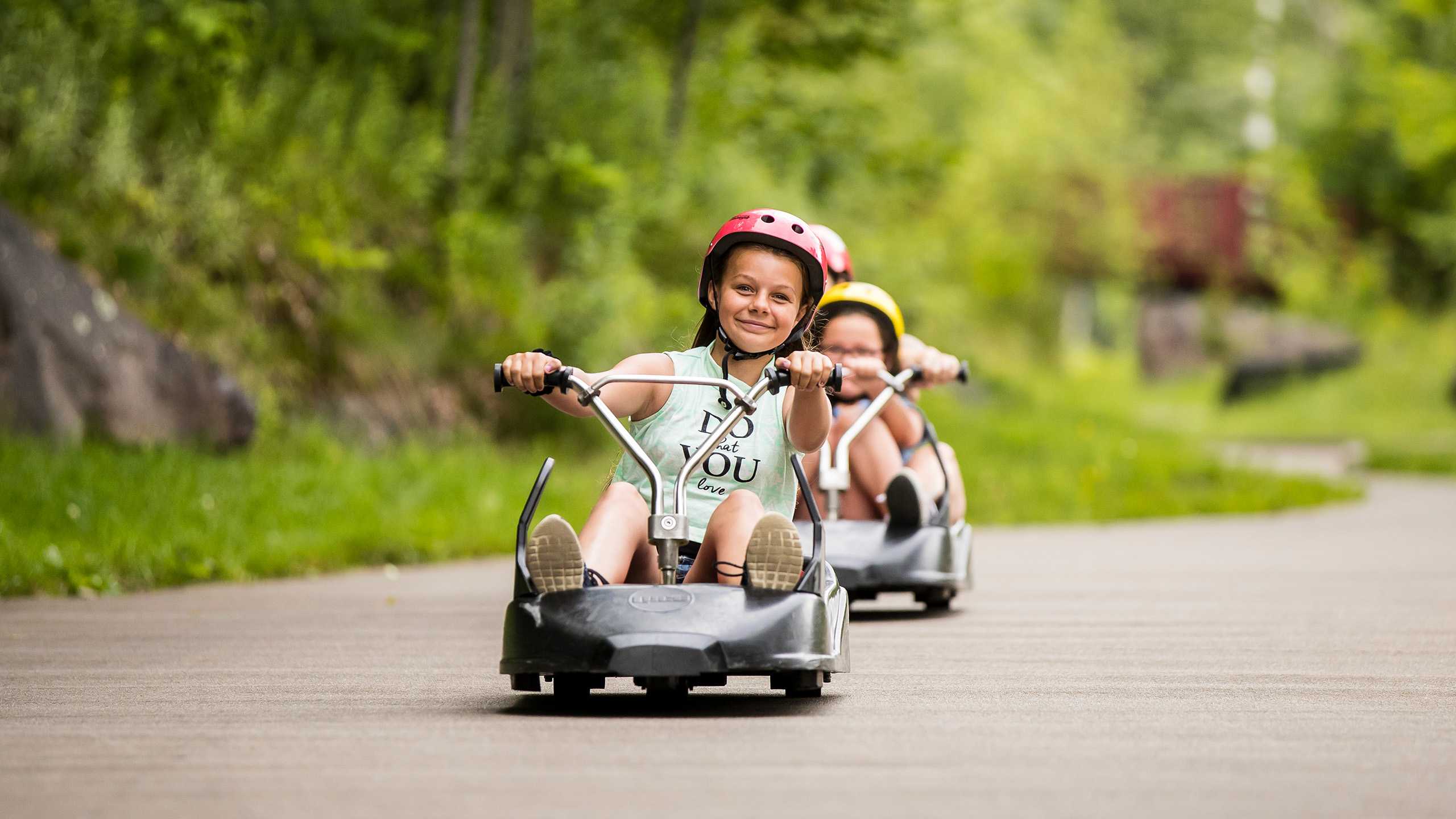 A small girl smiles and rides down the tracks at Skyline Luge Mont Tremblant.